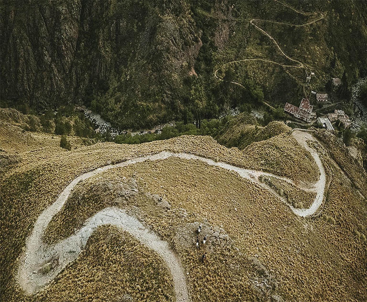 Vista aérea del camino serpenteante que baja al valle hacia Carahuasi, una capilla visible abajo
