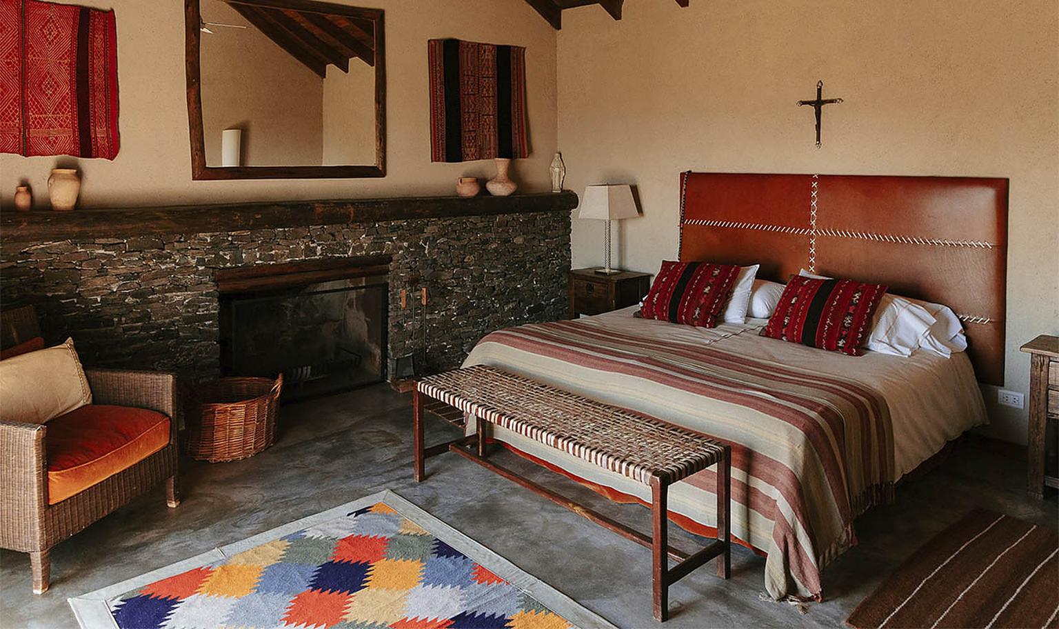 La suite principal de Carahuasi — chimenea de piedra, kilim y textiles artesanales